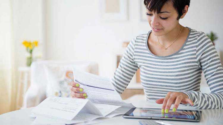 Una mujer en su computadora portátil revisando la información sobre préstamos del plan 401k y retiros de efectivo del 401k.