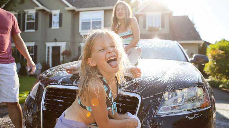 Una familia está en casa lavando su carro recientemente refinanciado.