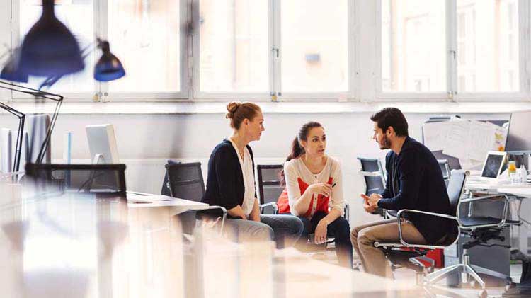 Empleados sentados en una oficina hablando sobre los planes de pensiones simplificados para empleados.