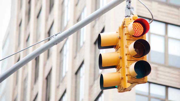 Semáforo rojo con un edificio de apartamentos al fondo.