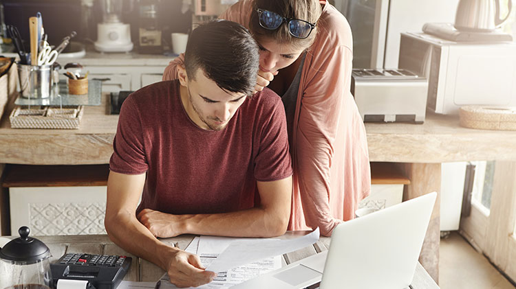 Pareja revisa su presupuesto en una mesa de su casa.