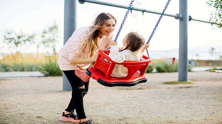 Mamá empujando a su hija en el columpio