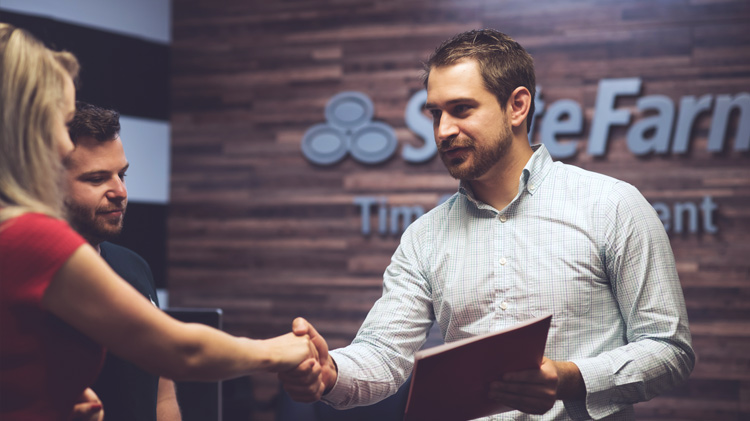 Un agente de State Farm estrechándole la mano a una señora.