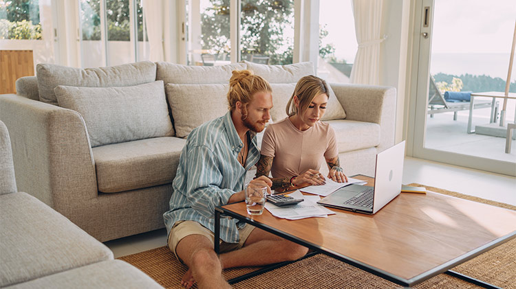 Una pareja mirando una computadora y hablando sobre cómo pagar su hipoteca.