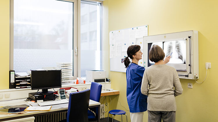 Mujer y un proveedor médico revisando radiografías
