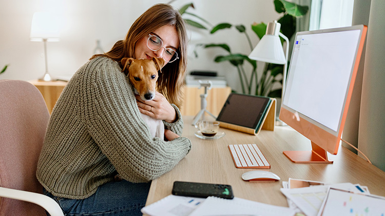 Mujer joven estudiando en casa con su cachorro Jack Russell.