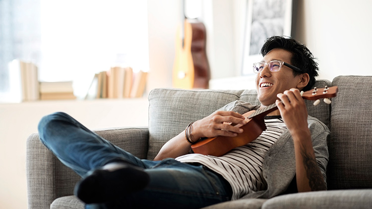 Hombre joven tocando el ukulele pensando en cuanto seguro de inquilinos necesita
