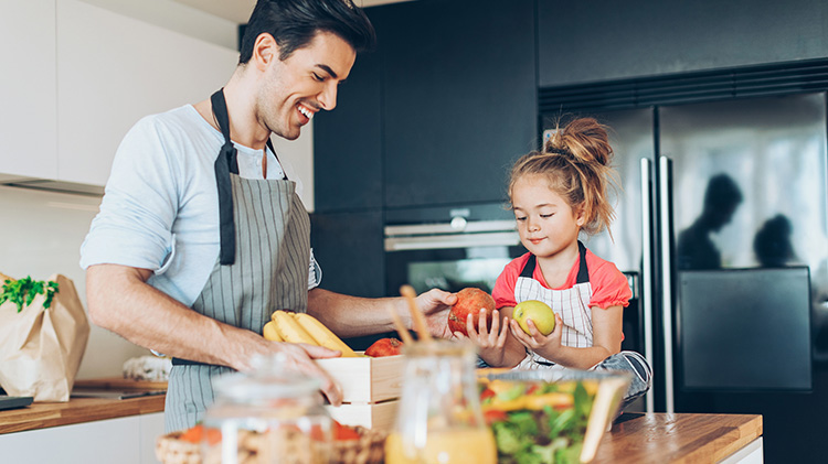 En el verano, un hombre y su hija revisan frutas y verduras frescas antes de cocinar.