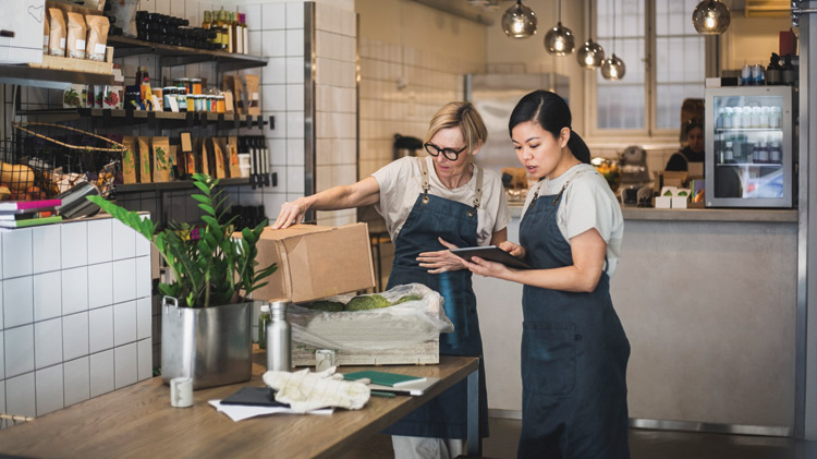 Emprendedoras hablando ante una tableta digital en una tienda.