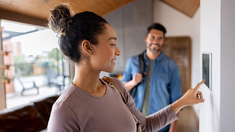 Una pareja saliendo de su vivienda y activando la alarma usando un sistema automático de vivienda
