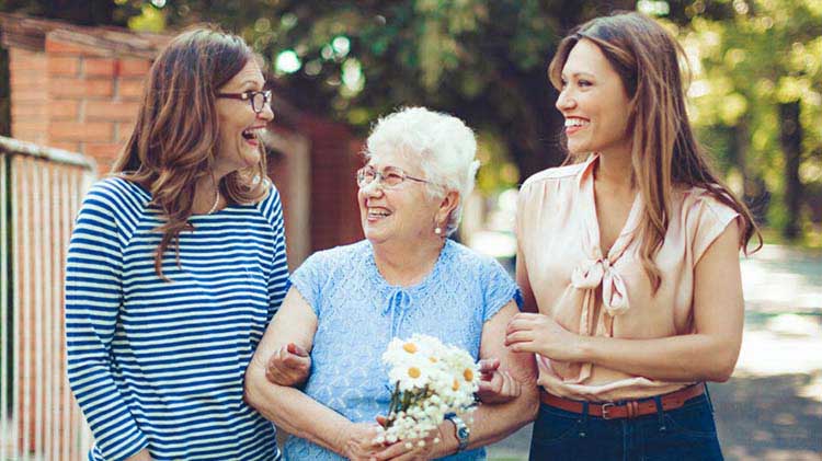Tres generaciones de mujeres caminando y hablando sobre las opciones de vivienda para personas de la tercera edad.