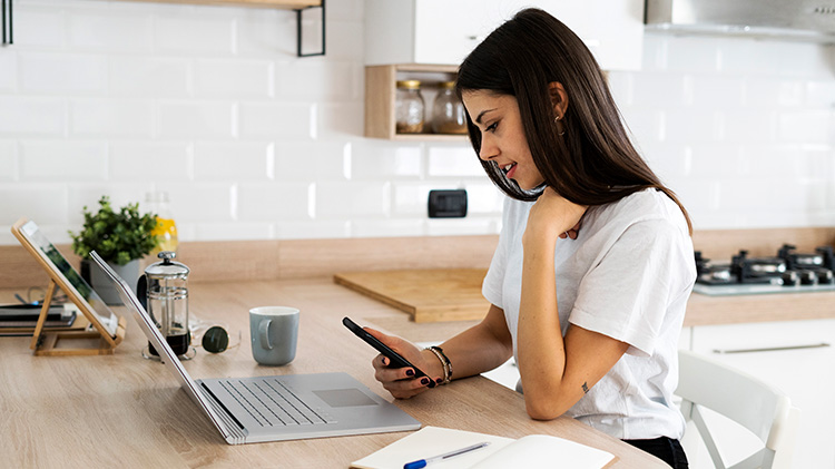 Una mujer joven está en su cocina revisando sus pólizas de seguro
