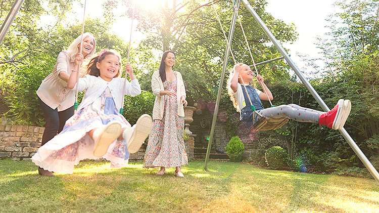 Dos mujeres columpiando a niñas pequeñas en un parque infantil.