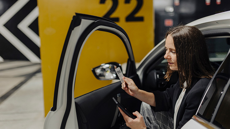 Una mujer saliendo de un carro en un estacionamiento.