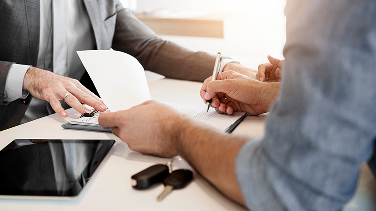 Una persona firma la documentación para un alquiler de carro