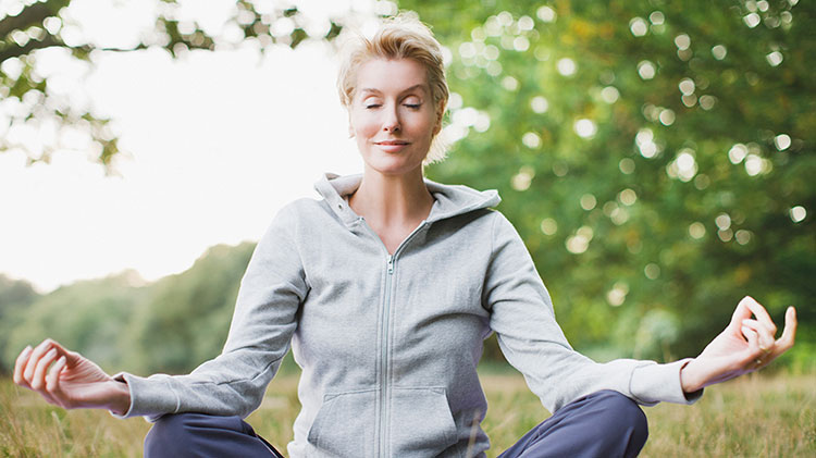 Mujer meditando al aire libre.