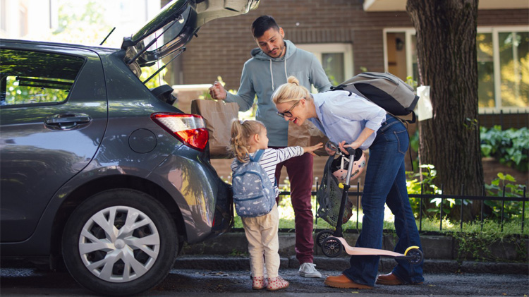 Una familia feliz empacando cosas en la parte trasera del auto.