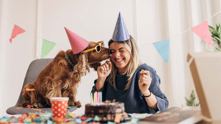 Una mujer celebrando el Adoptaniversario de su perro con su amigo peludo en casa.