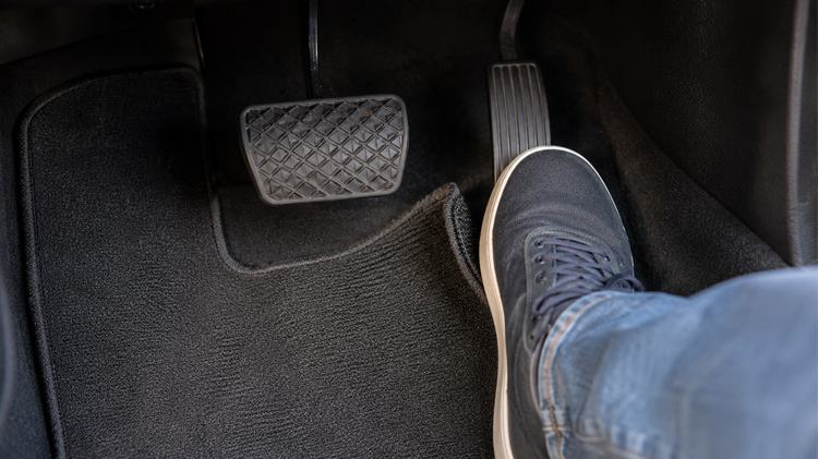 El pie del conductor cerca del freno y del pedal de aceleración en el espacio para los pies del carro.