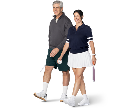 Una pareja sonriente se dirige a la cancha de pickleball.