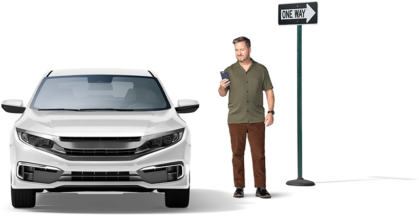 Junto a una señal de calle de sentido único, un hombre revisa su teléfono inteligente mientras llega su transporte.