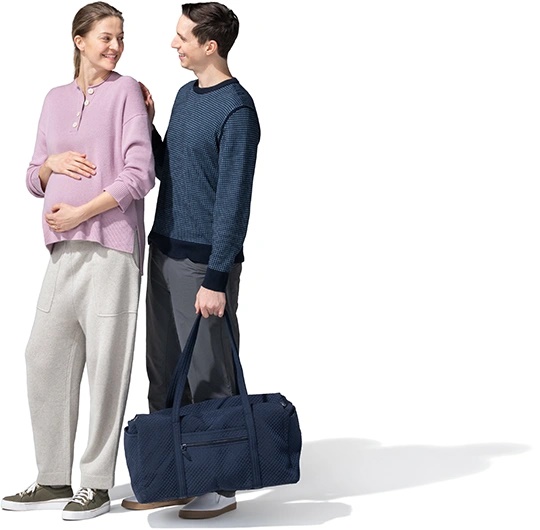 Mujer embarazada con su marido llevando una maleta.