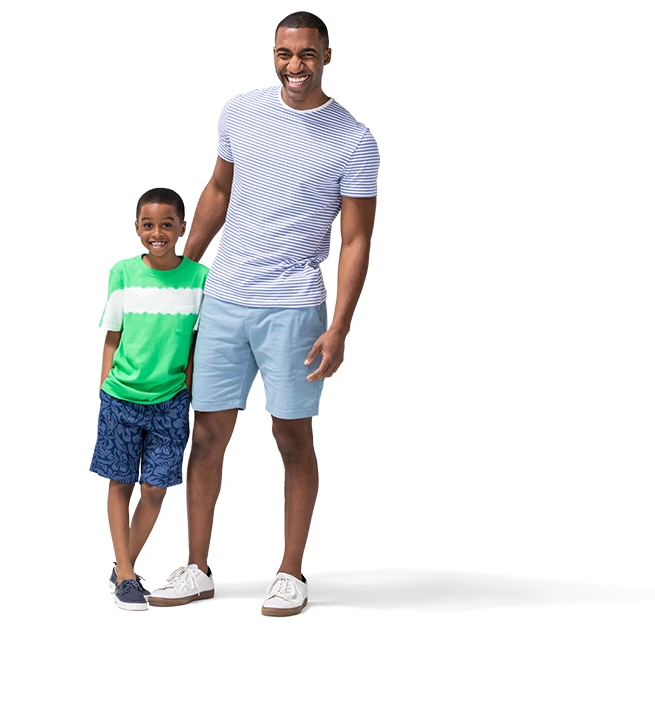 Con pantalones cortos y camiseta, un niño pequeño se recuesta contra su padre.